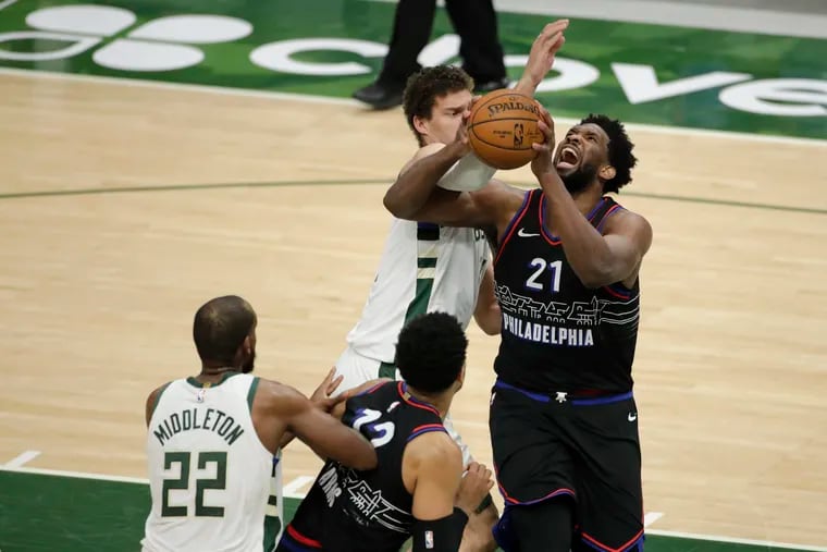 Joel Embiid trying to shoot in Thursday's loss as Milwaukee's Brook Lopez defends him.