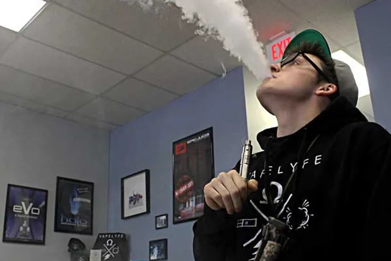 Cole Mentzer, a sales associate at Popie's Vapor Lounge, exhales vapor after taking a drag from his e-cig, in Marlton, New Jersey on Thursday, April 24, 2014. ( COURTNEY MARABELLA / Staff Photographer )
