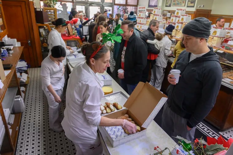 Salesperson Kristi Carr loads up a box of cannoli for customer Sean McMullan of Society Hill, Philadelphia, at Termini Bros. Pastries in South Philadelphia on Dec. 24, 2019. The pandemic necessitated a pivot this year. But the tradition of lining up at Termini on Christmas Eve will live.