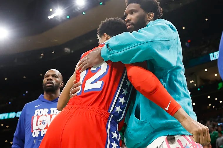 Injured Sixers center Joel Embiid hugs forward Tobias Harris before the start of Game 1 of the Eastern Conference semifinals in Boston  on Monday.