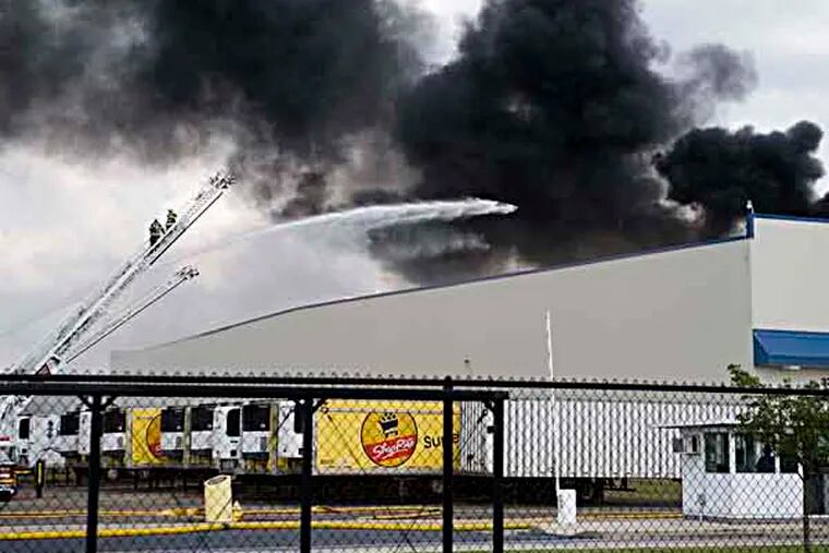 Firefighters work to containa multi-alarm blaze that reportedly started with a refrigeration unit on the roof at the Dietz and Watson warehouse on Coopertown Road in Delanco on Sunday, Sept. 1, 2013. (AP Photo/ Camden Courier-Post, Jodi Samsel)