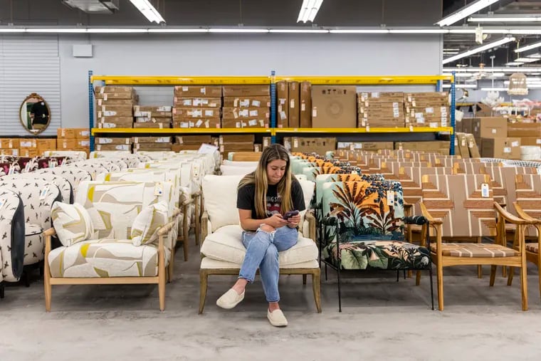Natalie Lukasik, 30, of East Falls, associate at Anthropologie's Marlton location, helps customers tag chairs they are planning to buy during the Anthropologie pop-up furniture sale at the Philadelphia Mills Mall.