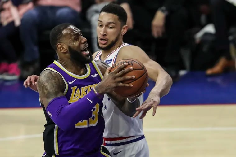 LeBron James tries to drive around the Sixers' Ben Simmons.