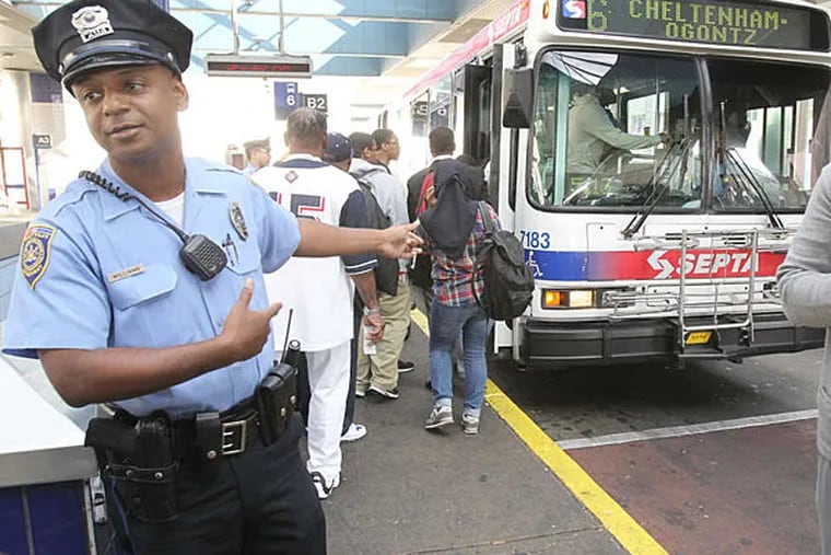 Transit police officer Paul Williams tells students to move along or board the bus at the Olney Transportation Center. (Charles Fox/Staff)