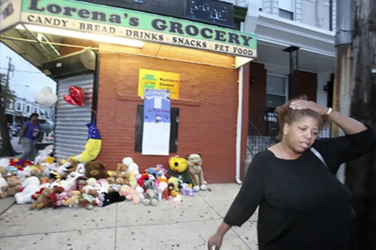 A mourner leaves after leaving a memento at the memorial outside Lorena's Grocery at 50th and Parrish, where three people were killed Tuesday. (Steven M. Falk / Staff Photographer)