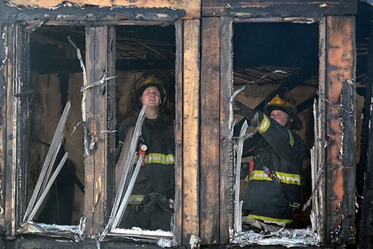 Firefighters work at the scene of fire that ripped through eight rowhomes in Southwest Philadelphia killing four children July 5, 2014. ( TOM GRALISH / Staff Photographer )