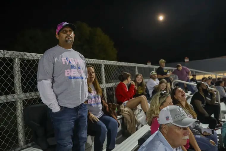 Juan Namnun sits next to his wife, Lena Namnun, as they watch two of their sons play in a football game at Rancocas Valley Regional High School in Mt. Holly on Friday.  Namnun, a former baseball player turned longtime coach and educator at Frankford High School, is battling breast cancer.