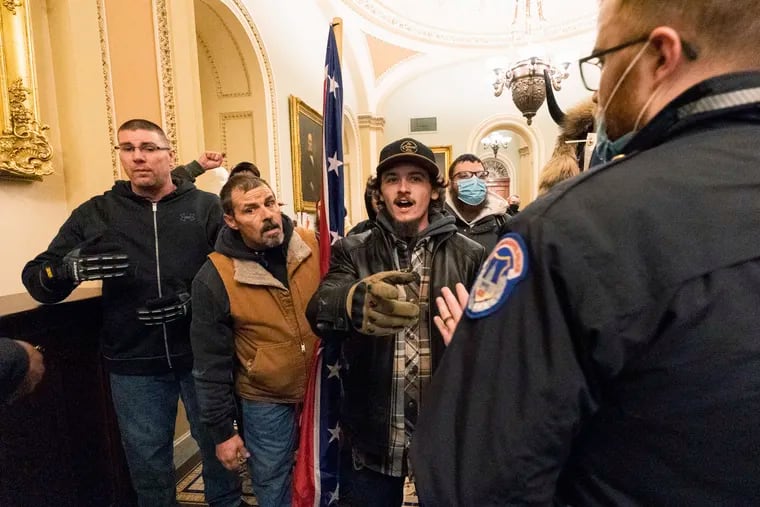 Kevin Seefried, second from left, holds a Confederate battle flag as he and other insurrectionists loyal to President Donald Trump are confronted by U.S. Capitol Police officers outside the Senate Chamber inside the Capitol in Washington on Jan. 6, 2021.
