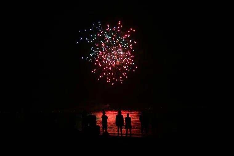 Spectators stand in the water at Ocean City, N.J. to watch the Fourth of July fireworks in 2018.