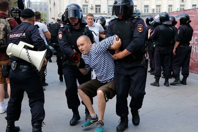 Police officers detain a man during an unsanctioned rally in the center of Moscow, Russia, Saturday, July 27, 2019. Russian police on Saturday began arresting people outside the Moscow mayor's office ahead of an election protest demanding that opposition candidates be allowed to run for the Moscow city council.