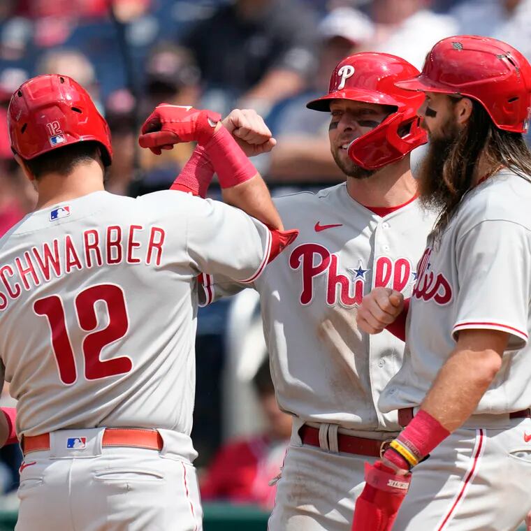 Philadelphia Phillies' Kyle Schwarber, left, celebrates with teammates Drew Ellis, center, and Brandon Marsh after batting them in on a home run.