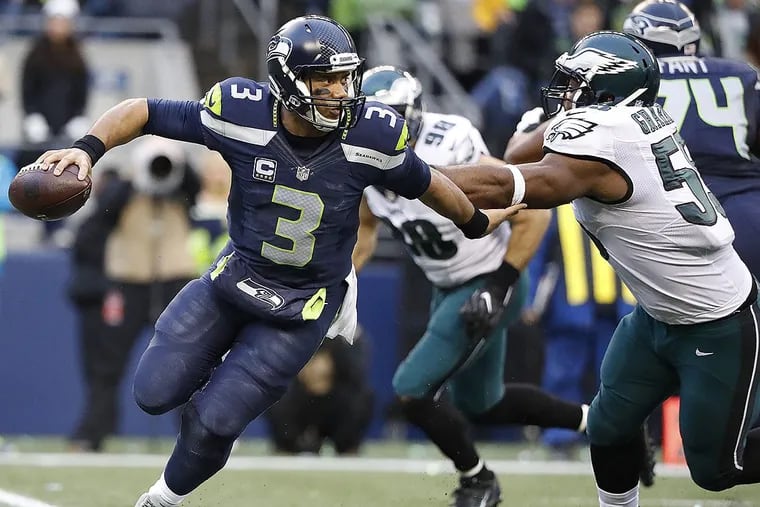 Seahawks quarterback Russell Wilson scrambles away from the Eagles’ Brandon Graham.