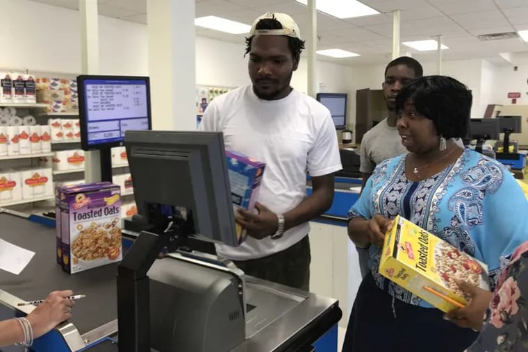 Cashier in training Keith Choice, gets tips on how to work the register. He was formerly incarcerated and now hopes to start a new life as a cashier at ShopRite.
