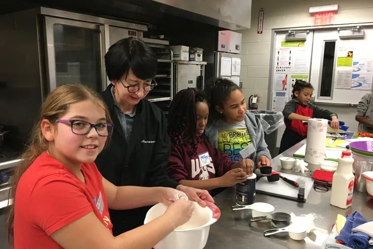Melanie Ronen mixes biscuit dough with volunteer Suzanne Penn, while Morgan Pettiford and Suriyah Washington measure ingredients at Wissahickon Charter School Awbury campus.