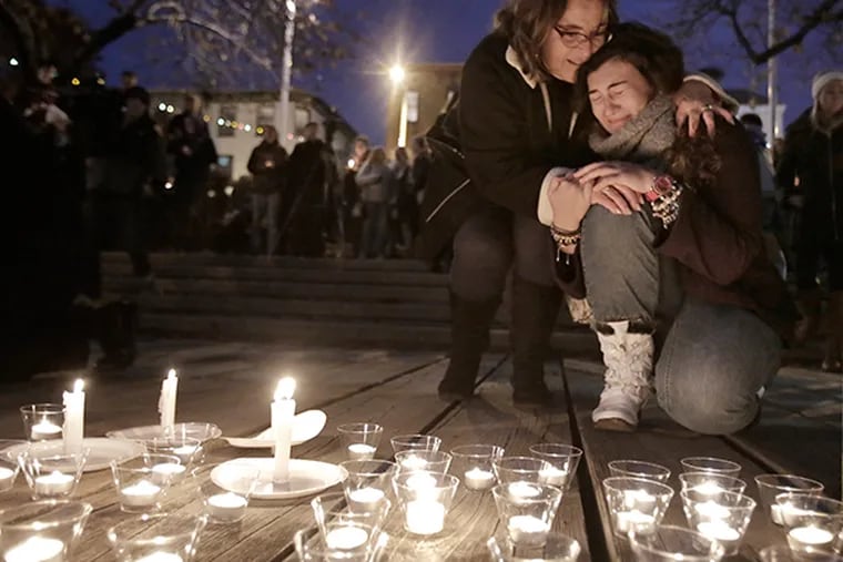 After leaving a candle at the edge of the Manayunk Canal, a woman is comforted by another during a candlelight vigil, for Shane Montgomery, at a park across from Kildare's Irish Pub at 4417 Main St. in Manayunk on Nov. 29, 2014. Montgomery, who is still unaccounted for, was last seen leaving Kildare's on Thanksgiving Eve. (Elizabeth Robertson / Staff Photographer)