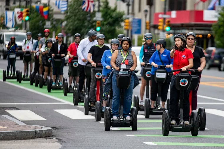 Sophia Rosser (red shirt), a Segway tour guide, leads a group of Greater & Greener conference attendees along the Benjamin Franklin Parkway on Saturday.
