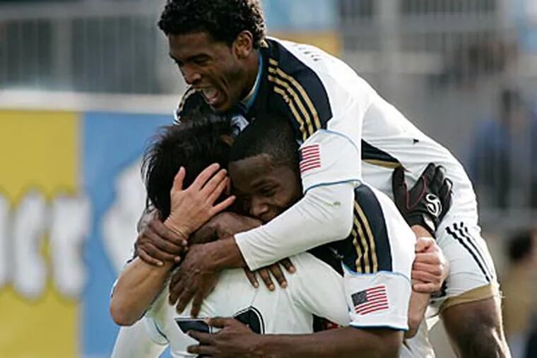Sheanon Williams (top) and Danny Mwanga (center) celebrate a goal by Carlos Ruiz. (Tom Mihalek/AP Photo)