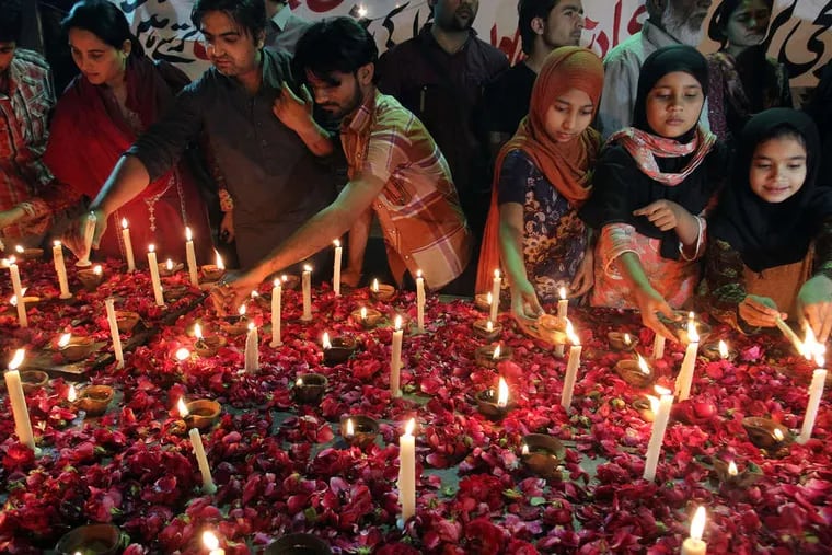 In Karachi, Pakistan , people light candles for bombing victims at a vigil. The attacks in Lahore came during Sunday services. Christian mobs retaliated. FAREED KHAN / Associated Press
