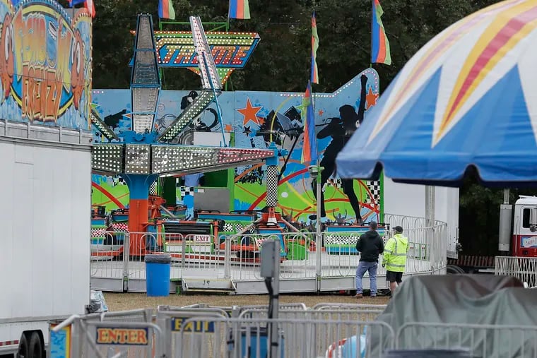 Two men look at the "Xtreme" amusement ride at the Deerfield Township Harvest Festival on Sunday, the day after a 10-year-old girl was thrown from the ride to her death.