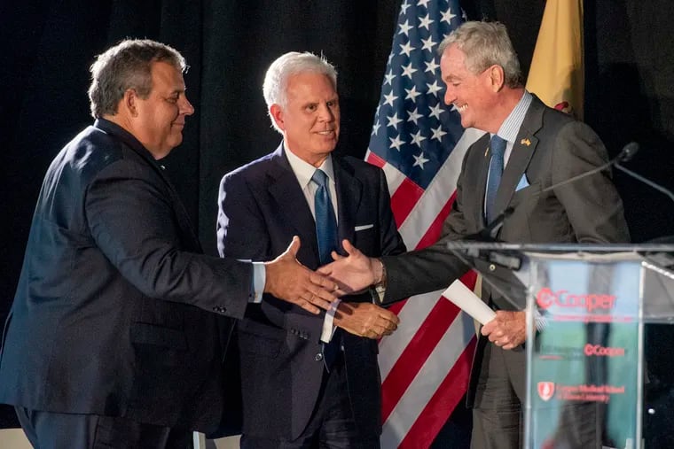 South Jersey power broker George E. Norcross III (center) is on stage with Gov. Phil Murphy (right) and former Gov. Chris Christie (left) on Sept. 19, 2022, as Cooper University Health Care and MD Anderson Cancer Center at Cooper announce a $2 billion expansion in Camden. Norcross is chair of Cooper University Health Care's board.