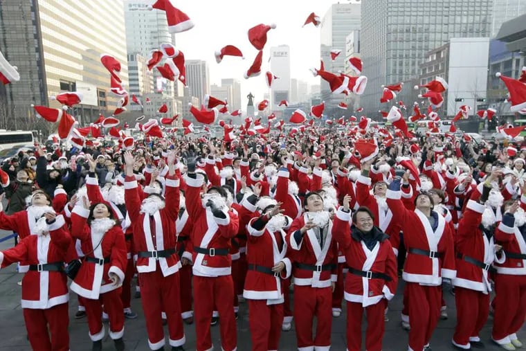 More than 1,000 volunteers clad in Santa Claus costumes throw their hats in the air as they gather to deliver gifts for the poor in downtown Seoul, South Korea, Tuesday, Dec. 24, 2013. (AP Photo/Lee Jin-man)