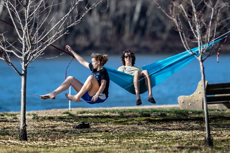 Claire Fucetola tries to keep her balance as she begins a slacklining lesson given by her brother Rocco along Kelly Drive on a warm and sunny January day. Rocco, in the hammock, has been doing slackline for about three years.
