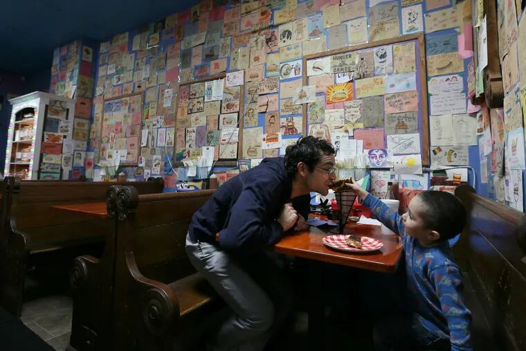 David Laverdure takes a bite of a grilled cheese sandwich from his son, Bodhi, 3, inside Sketch Burger. The Fishtown eatery with malt shop flair and customer doodles adorning the walls makes a great burger and outstanding chili, as well.