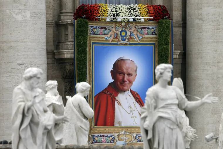 The tapestry showing Pope John Paul II hangs from the facade of St. Peter's Basilica during a solemn celebration led by Pope Francis I where two Popes, John Paul II  and John XXIII, were canonized, in St. Peter's Square at the Vatican, Sunday, April 27, 2014. (AP Photo/Alessandra Tarantino)