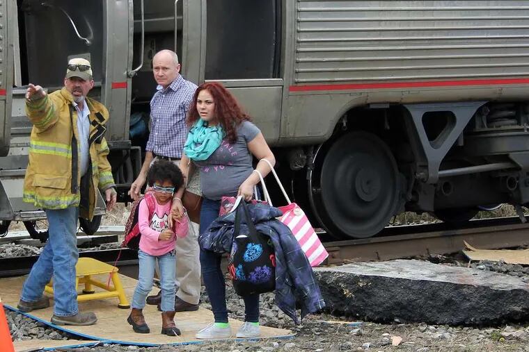 ERIN CARSON / ASSOCIATED PRESS Passengers Alyssa Coleman (right) and her little sister, Viara Hinton, are helped off the derailed Amtrak by workers on the scene.