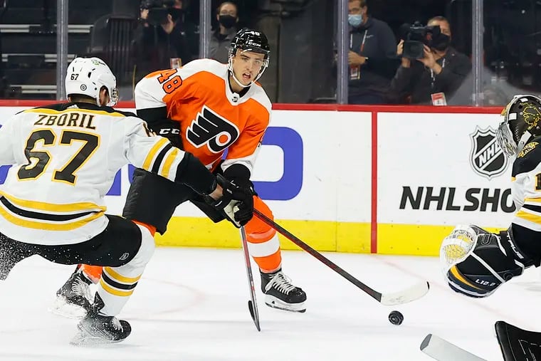 Flyers center Morgan Frost moving the puck against Boston Bruins defenseman Jakub Zboril and goaltender Jeremy Swayman in a preseason game on Oct. 4.