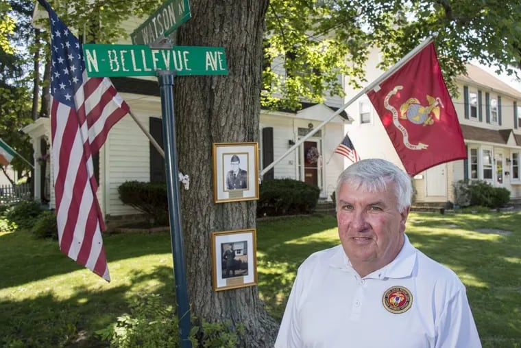 John Rumsey, 65, a U.S. Marine and Vietnam combat veteran who was awarded the Purple Heart, is among 200 volunteers bringing the Vietnam Traveling Memorial Wall to Penndel in July.  He stands outside his Langhorne home, where framed photos of  two young men from the nearby street where his wife grew up are displayed on the maple tree in his front yard.