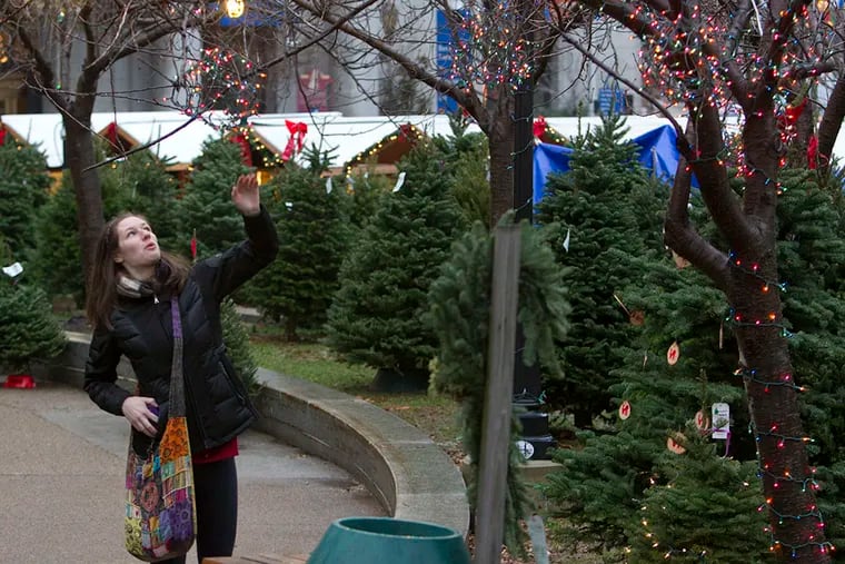 A woman stops to admire the lights as she walks through the Christmas Tree Stand at LOVE Park on Dec. 16, 2014. ( CHARLES FOX / Staff Photographer )