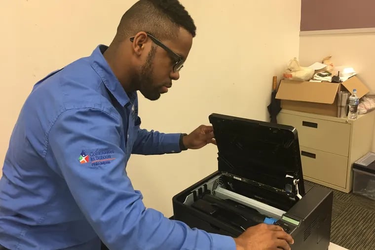 Shabazz Ransom, an IT apprentice, troubleshooting an issue with a printer at his worksite site, Philadelphia Learning Academy North, in March 2018.