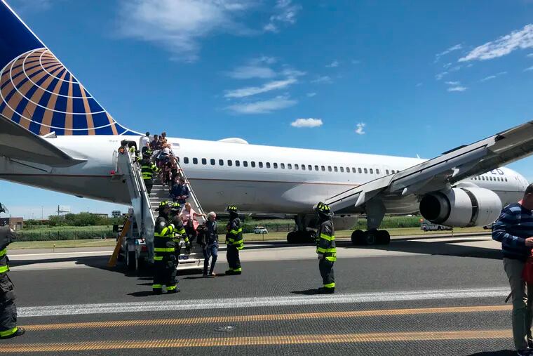 This photo provided by Caroline Craddock shows emergency personnel help passengers off a plane after a  United Airlines plane skidded off the runway after landing at Newark Liberty International Airport on Saturday, June 15, 2019 in Newark, N.J.  (Caroline Craddock via AP)