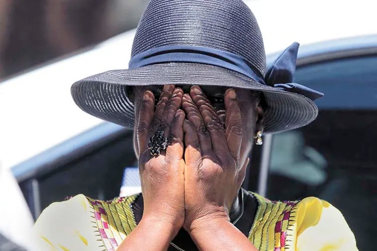 Roselyn Gray, God Mother to the twins who died in a row home fire early Saturday, covers her face after meeting with the media on 6500 block of Gesner Street in Southwest Philadelphia on Sunday, July 6, 2014.   ( YONG KIM / Staff Photographer )