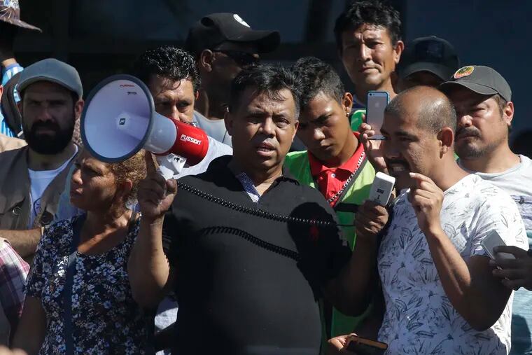 FILE - In this Oct. 22, 2018 file photo, migrant activist Irineo Mujica, center, of the group Pueblo Sin Fronteras or People Without Borders,  holds a megaphone as a Central American migrant speak to reporters during a press conference in Tapachula, Mexico. The activist group that escorted thousands of Central Americans to the U.S. border is under fire from allies and some of the migrants themselves. They say the organization downplayed the dangers of the trek and misled them about how long they would have to wait around to apply for asylum. Pueblo Sin Fronteras, or People Without Borders, is defending itself, saying the migrants made their own decision to press on toward the United States. (AP Photo/Moises Castillo)