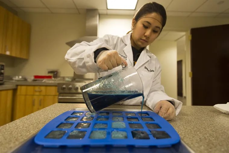 Kira Sy, a Masters candidate at Drexel University College of Nursing and Health Professions, pours a hot syrup into molds to make Dragon Gels.