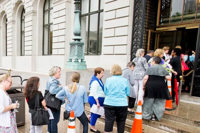 A long line of people waiting to see Hillary Clinton winds out of the Central Branch of the Free Library of Philadelphia. Hillary Clinton will be at the Free Library of Philadelphia on Friday morning June 13, 2014 to sign copies of her new book, Hard Choices. This large group of people gathered outside the library with tickets to see and have their book signed. ( ALEJANDRO A. ALVAREZ / STAFF PHOTOGRAPHER )