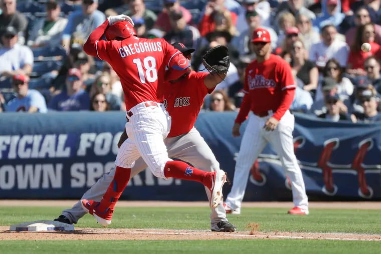 Phillies Didi Gregorius leaps safely towards first base against Red Sox first baseman Josh Ockimey.  Gregorius advanced to first on a strike out passed ball.