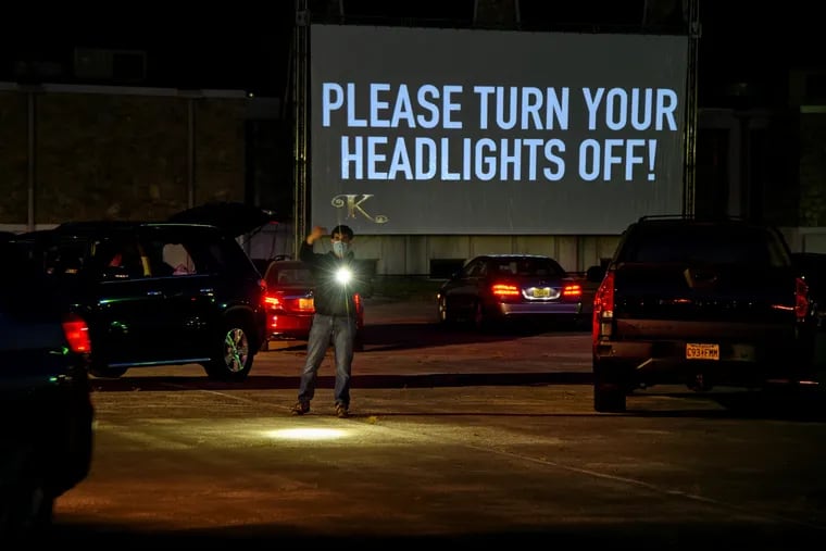 Stephen Calascione uses a flashlight to direct vehicles into their socially distanced spaces at the pop-up drive-in theater — Karpool Cinema — in the parking lot of the Kathedral Event Center in Hammonton on Thursday. Families in 44 cars, vans, SUVs and pickups watched "Sonic The Hedgehog" on a 40-foot screen.