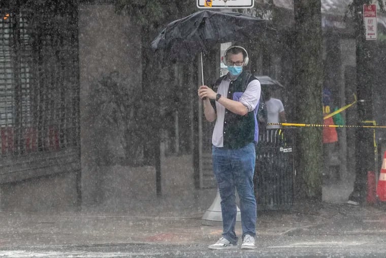 A masked pedestrian along 40th and Chestnut Streets battled heavy rain and blowing wind on Tuesday morning while health officials announced some "good news" regarding the city's coronavirus case totals.