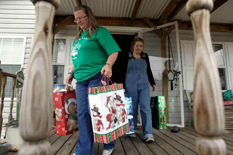 Vickie Perrin (left) and Joannie Hughes carry Christmas gifts they plan to distribute to 112 families in Jesuit Bend, La.