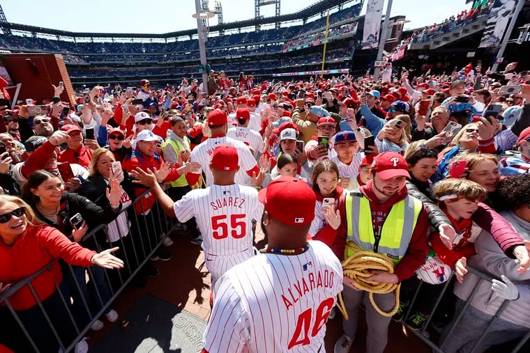 Phillies players greet fans during opening day ceremonies on Friday. Starting in two weeks, they'll no longer be wearing those white uniforms for Friday home games.