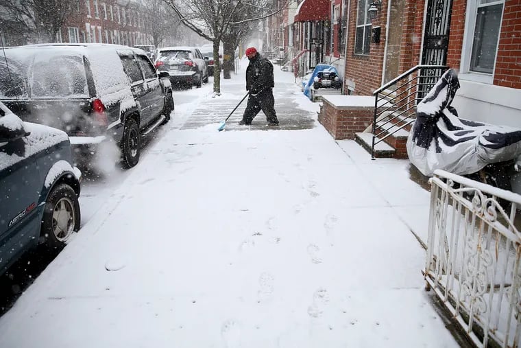 Boi Heng shovels snow in front of his and his neighbors' homes on Wolf Street in South Philadelphia on Wednesday.
