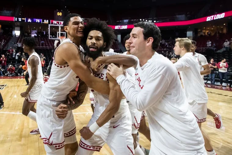 Damian Dunn, center, of Temple, is swarmed by teammates Nick Jourdain, left, and Colin Daly, right, after hitting a 3-pointer to give Temple a 78-75 victory over East Carolina at the Liacouras Center on Jan. 8, 2022.