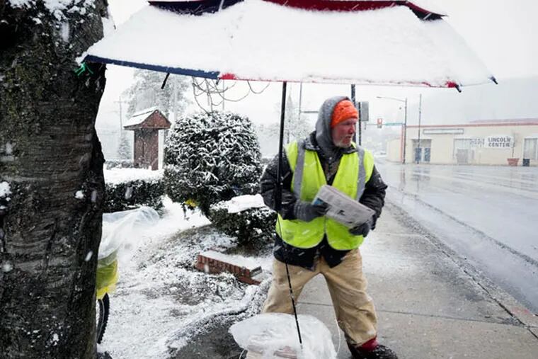Newspaper vendor Roger Tize stands under his snow-covered umbrella on 1st Street in Coatesville, Chester County, as he sells papers Friday, March 20, 2015. ( ED HILLE / Staff Photographer )
