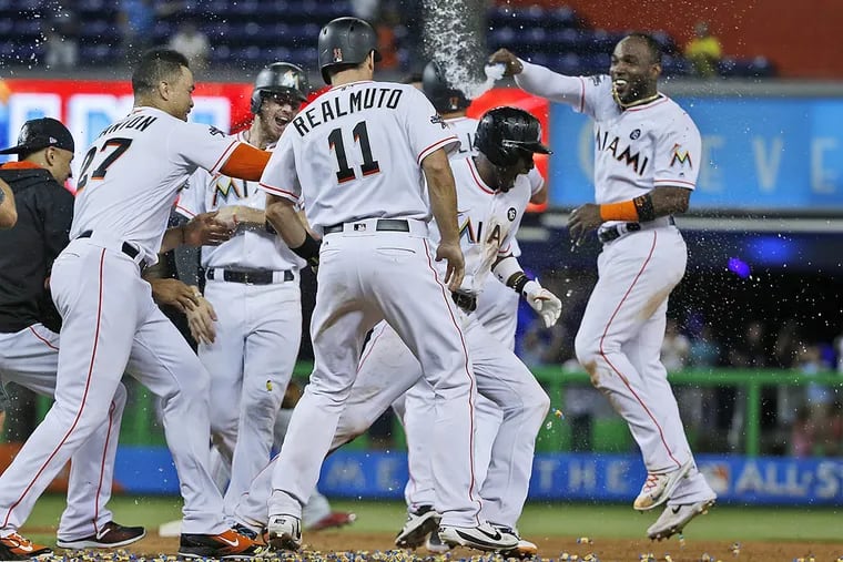 Miami Marlins' Dee Gordon, second from right, is mobbed by teammates after hitting a single to score J.T. Realmuto to beat the Philadelphia Phillies 6-5 in the 10th inning of a baseball game, Monday, July 17, 2017, in Miami.