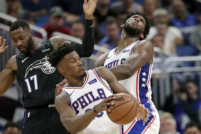 Jimmy Butler, center, collides with teammate Joel Embiid, right, as he tries to get around the Magic's Jonathon Simmons during the second half.