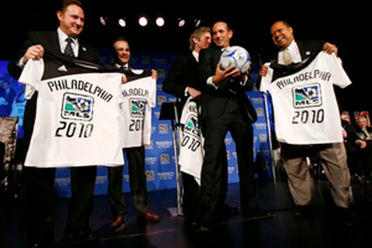 MLS commissioner Don Garber grabs a ball as team owners (from left) Nick Sakiewicz, Robert Buccini, Jay Sugarman and James Nevels hold T-shirts Garber gave them. &quot;We&#0039;re going to build a team, a stadium, and we&#0039;re going to lift some trophies along the way,&quot; Sakiewicz declared.