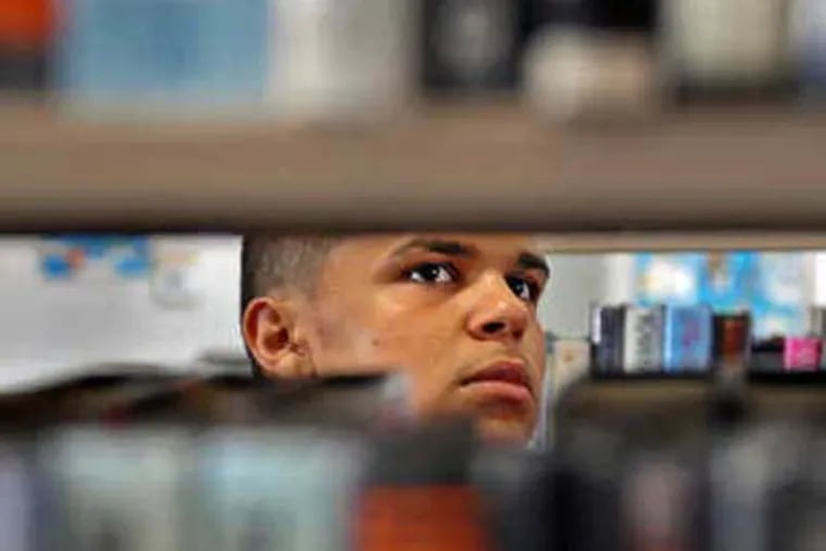 Pedro Munoz, 17, of North Camden, searches for summer reading in the downtown library. Students may not have access to a free library in 2011. (Tom Gralish / Staff Photographer)